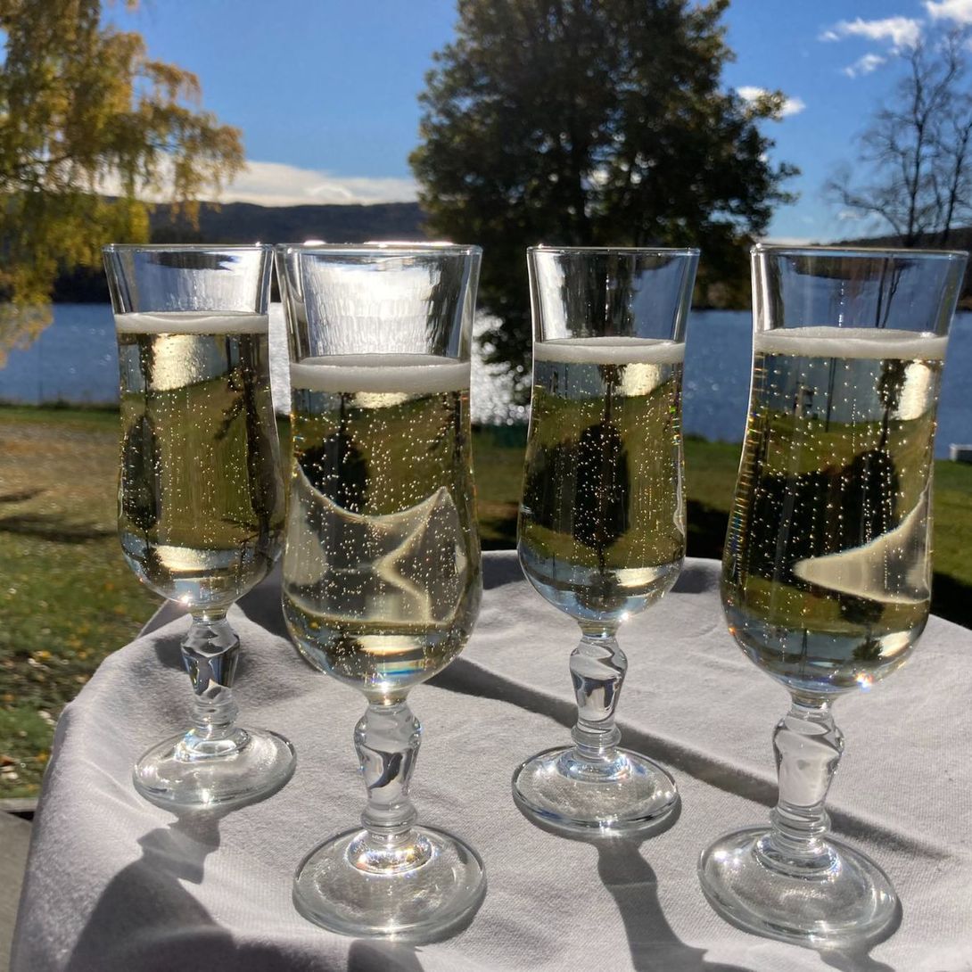 Sjampagneglass på bord ute ved innsjø