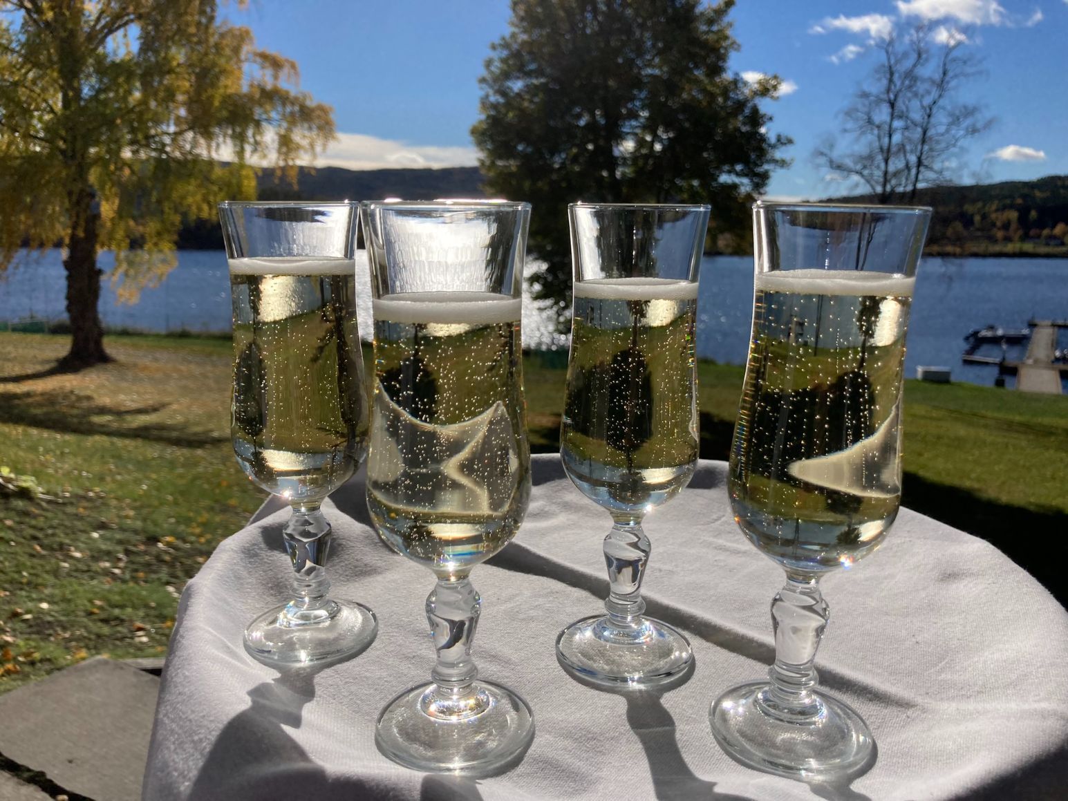 Sjampagneglass på bord ute ved innsjø